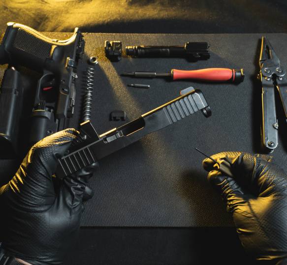 Gun disassembly with tools on table.
