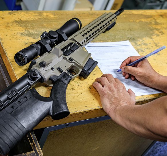 Rifle on table with person writing form.