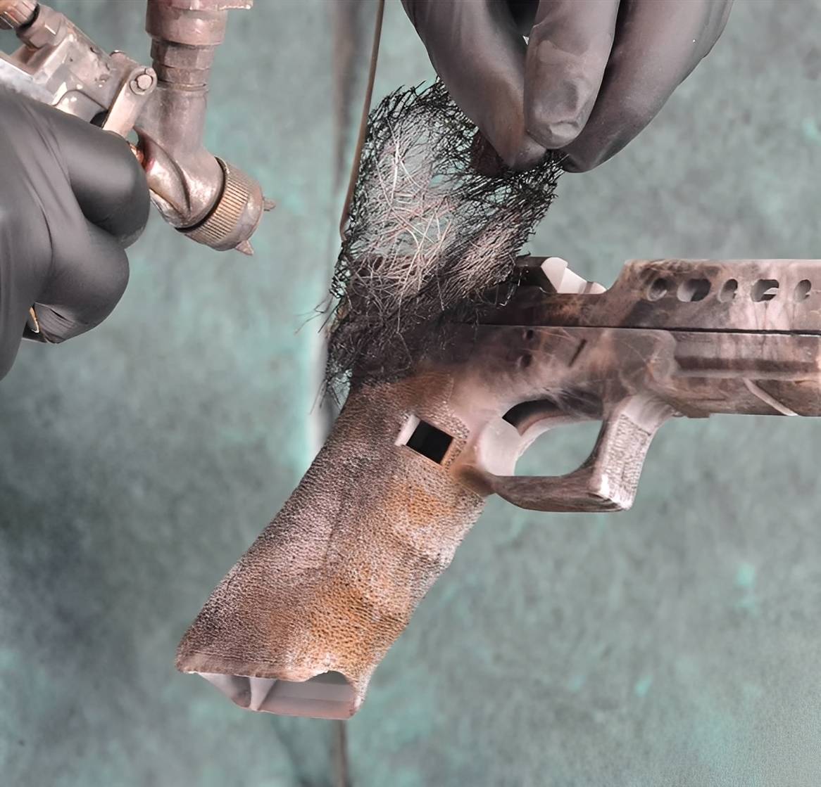 Spray painting a camouflage pattern on gun.