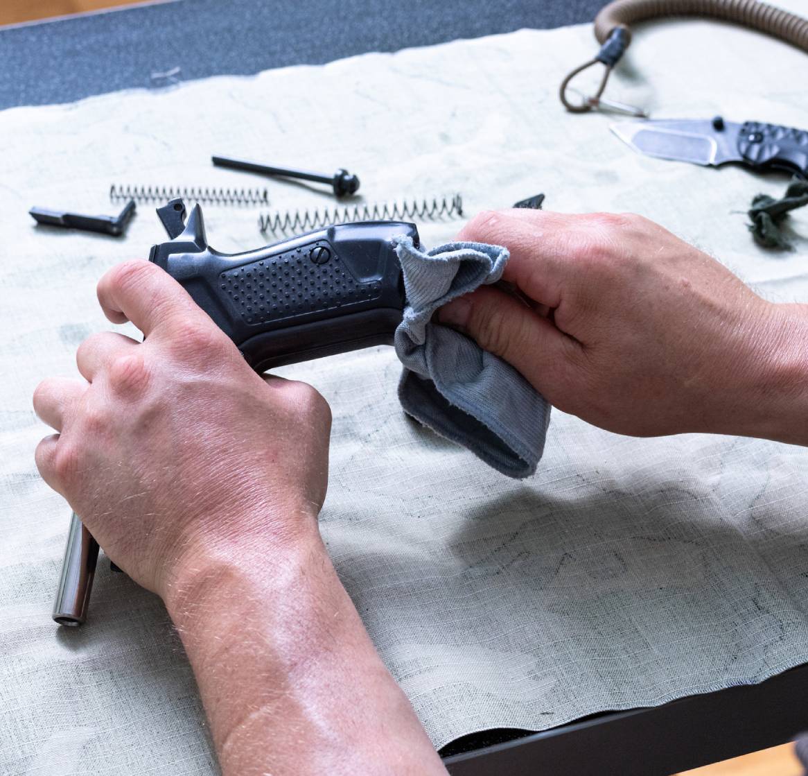 Cleaning a disassembled handgun on table.