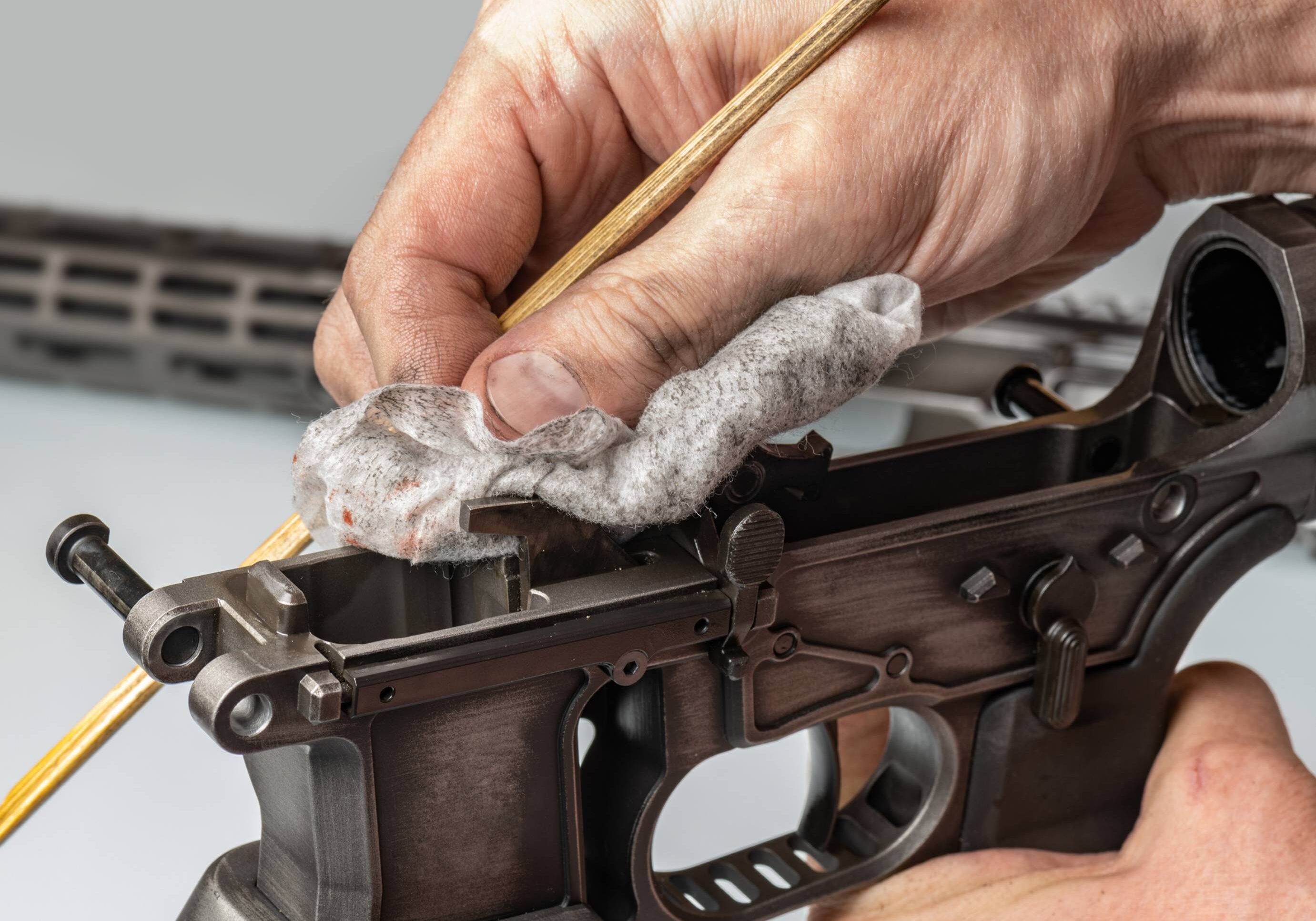 Cleaning firearm with cloth and stick.